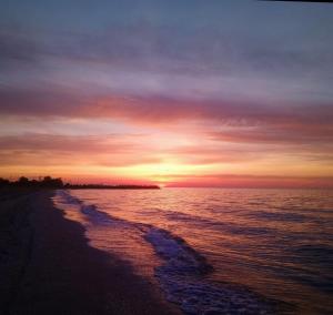 a sunset on a beach with the ocean at Apartament Bella in Jurilovca