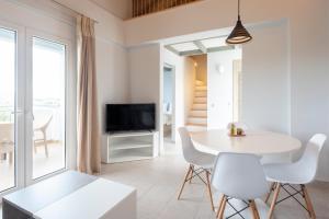 uma sala de estar com uma mesa e cadeiras e uma televisão em Kotroni Villas em Finikounta