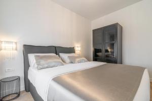ein weißes Schlafzimmer mit einem großen Bett und einem schwarzen Schrank in der Unterkunft Luxury Piano apartment in Zadar