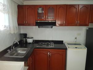 una cucina con armadi in legno, lavandino e piano cottura di Apto en Rodadero Palanoa 605 Dos Habitaciones 7 personas a Santa Marta