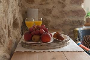 a plate of fruit on a table with two glasses of orange juice at Sobe Bile in Pag