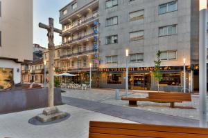 a wooden cross in front of a building with a bench at Hotel Virgen del Camino Pontevedra in Pontevedra