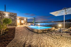 a swimming pool with an umbrella and some chairs at Klimata House - Private Jacuzzi Pool & BBQ Villa in Vlychada Beach
