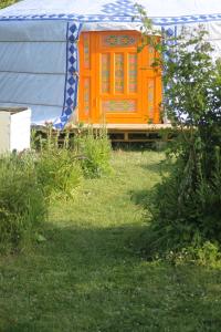 une porte orange d'une yourte dans une cour dans l'établissement Yourte Grain de Folie, à Waben