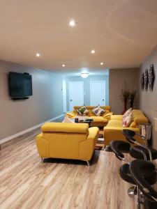 a living room with yellow couches and a flat screen tv at Serendib Bed and Breakfast in Stratford