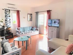 uma sala de estar com um sofá e uma televisão em Villa c/ piscina próxima da praia em Cabanas de Tavira