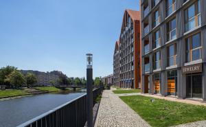 a building next to a river next to a building at Unique Motlawa Riverbank Apartment in Gdańsk