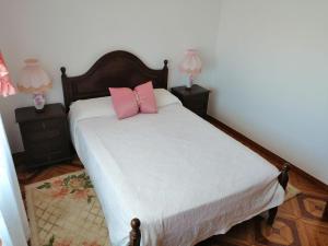 um quarto com uma cama com almofadas cor-de-rosa em Vivenda Ribeiro em Lagos