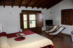 ハランディージャ・デ・ラ・ベラにあるComplejo Rural La Coronillaのベッドルーム1室(ベッド1台、椅子2脚、テレビ付)