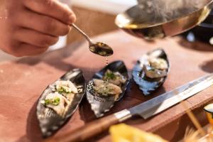 a person holding a spoon and five oysters on a table at TUI Blue Isla Cristina Palace - Adults Recommended in Isla Cristina