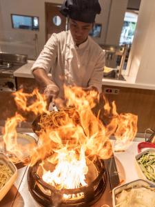a chef preparing food on a grill in a kitchen at TUI Blue Isla Cristina Palace - Adults Recommended in Isla Cristina