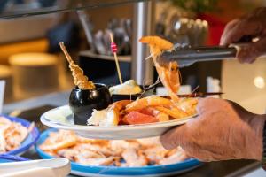 a person holding a plate of food on a table at TUI Blue Isla Cristina Palace - Adults Recommended in Isla Cristina