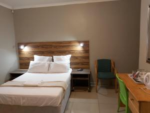una camera d'albergo con letto e scrivania con sedia di Hirondelle @ 45 Old Paarl a Bellville