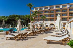 a row of lounge chairs and umbrellas in front of a hotel at TUI Blue Isla Cristina Palace - Adults Recommended in Isla Cristina