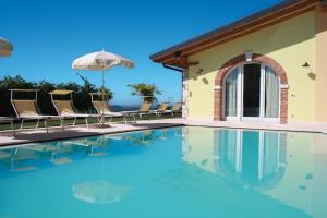 a swimming pool with chairs and an umbrella at B&B Al Cristo in SantʼAmbrogio di Valpolicella