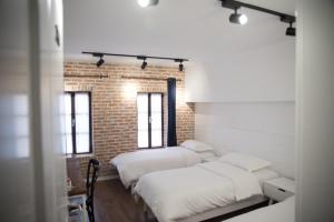 una camera con tre letti e un muro di mattoni di Old Bazaar Rooms a Korçë