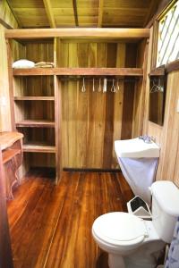 a bathroom with a toilet and a wooden floor at Hotel & Cabinas Nadine in Cahuita