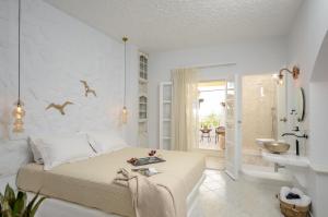 a white bedroom with a bed and a bathroom at Smirida Suites in Naxos Chora +95 photos