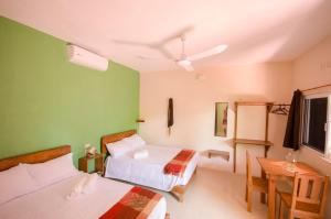 um quarto de hotel com duas camas e uma mesa e uma janela em Casa Almendro em Tulum