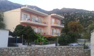 een groot roze gebouw met balkons op een muur bij Oasis Drymades Hotel in Dhërmi