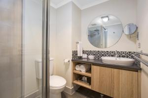 a bathroom with a toilet and a sink and a mirror at Quest Tamworth in Tamworth +8 photos