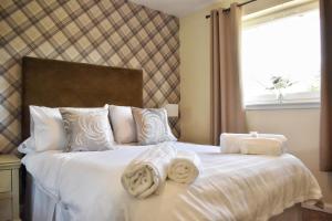 a bedroom with a white bed with towels on it at Ramblers Rest Modern Cottage-Perfect Views of Ben Nevis in Fort William