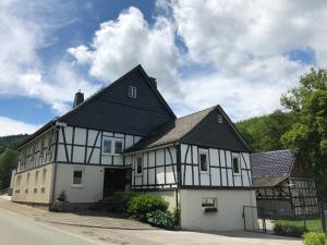 a white and black building with a black roof at Ferienhof Donner an der Wenne in Eslohe
