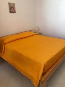 a bed with an orange blanket on top of it at Casa Vacanze Ciullo d'Alcamo in San Vito lo Capo