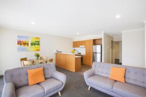 a living room with two couches and a kitchen at Quest Tamworth in Tamworth