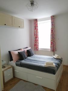 Un dormitorio con una cama con sábanas rosas y azules y una ventana en Dream Time Apartments-Aqua Suite, en Londres