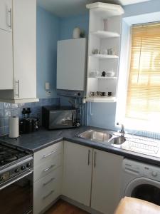 uma cozinha com armários brancos e um lavatório em Dream Time Apartments-Aqua Suite em Londres