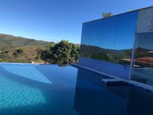 a building with a swimming pool with mountains in the background at Hotel Recanto do Ouro - Antigo Recanto da Serra in Ouro Preto