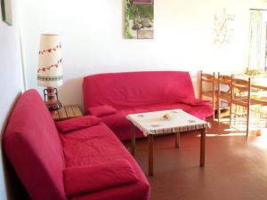 un soggiorno con divano rosso e tavolo di Appartement Camargue a Saintes-Maries-de-la-Mer