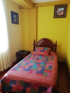 Un dormitorio con una cama con una colcha colorida. en El Marquez, en Tacna