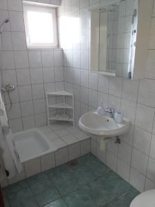 a white tiled bathroom with a sink and a shower at Apartments I-P in Malinska +19 photos