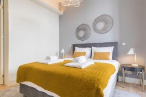 ein Schlafzimmer mit einem großen Bett und einer gelben Decke in der Unterkunft Ando Living - Santa Justa 79 Townhouse in Lissabon