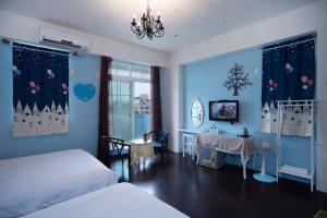 a bedroom with blue walls and a bed and a desk at Rose Castle in Taitung City