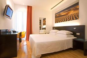 Habitación de hotel con cama, escritorio y TV. en Card International Hotel en Rímini