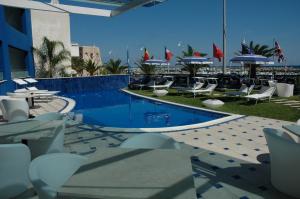 un resort con piscina con sedie e ombrelloni di Hotel Côte D'Est a San Foca