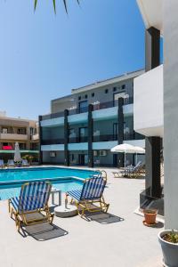 a swimming pool with two lounge chairs in front of a building at Yacinthos in Rethymno