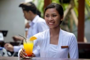 a woman sitting at a table with a drink at Villa Air Bali Boutique Resort and Spa in Seminyak