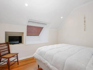 a white bedroom with a bed and a chair at Salt in Apollo Bay