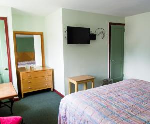 a bedroom with a bed and a dresser and a tv at Bay Drive Motel West Atlantic City in West Atlantic City