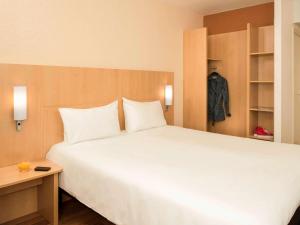 ein Schlafzimmer mit einem großen weißen Bett und einem Schrank in der Unterkunft ibis Nogent Sur Marne in Nogent-sur-Marne