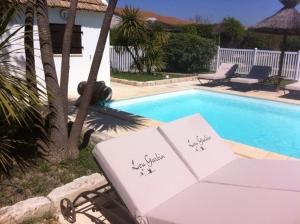 a pool with two opened umbrellas next to a table and a poolurity at Lou Garbin in Saint-Laurent-dʼAigouze