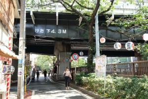 a person walking down a street under a bridge at COCO Nakameguro302 in Tokyo