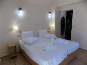 a white bed with white sheets and pillows on it at Souvlakis Pool Suites (S.P.S) in Chania +109 photos