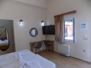 a bedroom with a bed and a desk and a television at Souvlakis Pool Suites (S.P.S) in Chania