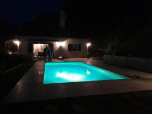 a swimming pool at night with two people standing around it at Villa les Bisets 497 rue de fenelon in Carlux +2 photos