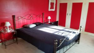 a bedroom with a bed with a red wall at Villa les Bisets 497 rue de fenelon in Carlux